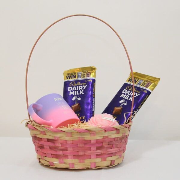 Gift basket with Cadbury Dairy Milk chocolate bars, pastel mug, and rose-scented candle