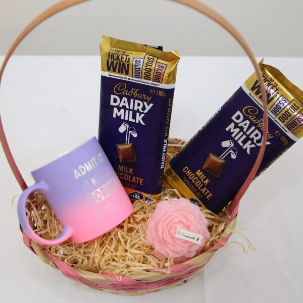 Gift basket with Cadbury Dairy Milk chocolate bars, pastel mug, and rose-scented candle